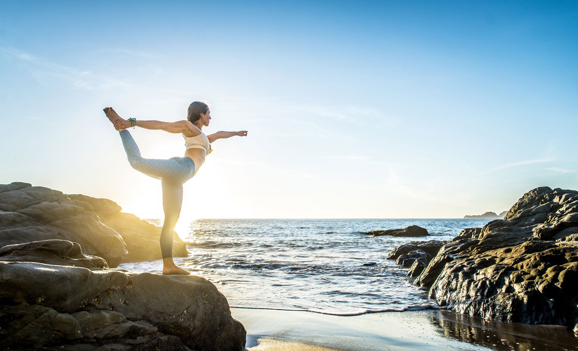 woman doing yoda over the ocean